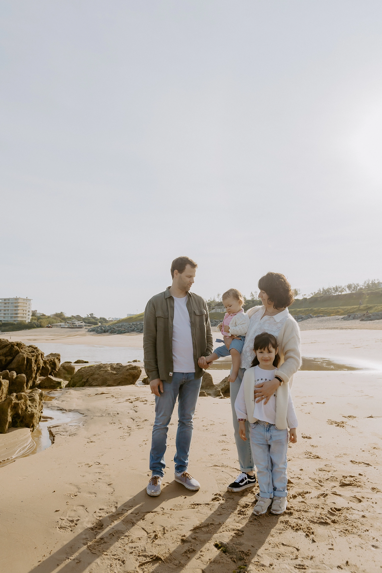 Famille unie sur le sable durant une séance de photos de famille sur la plage à Biarritz