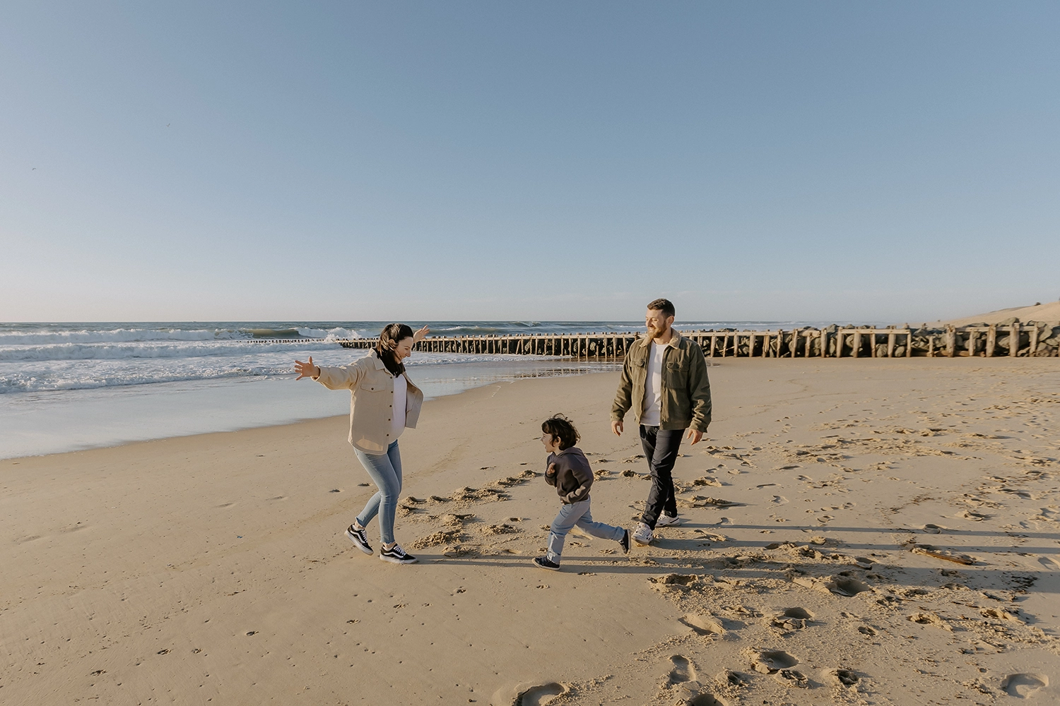 Famille sur la plage de Seignosse lors d’une séance photo grossesse en hiver.