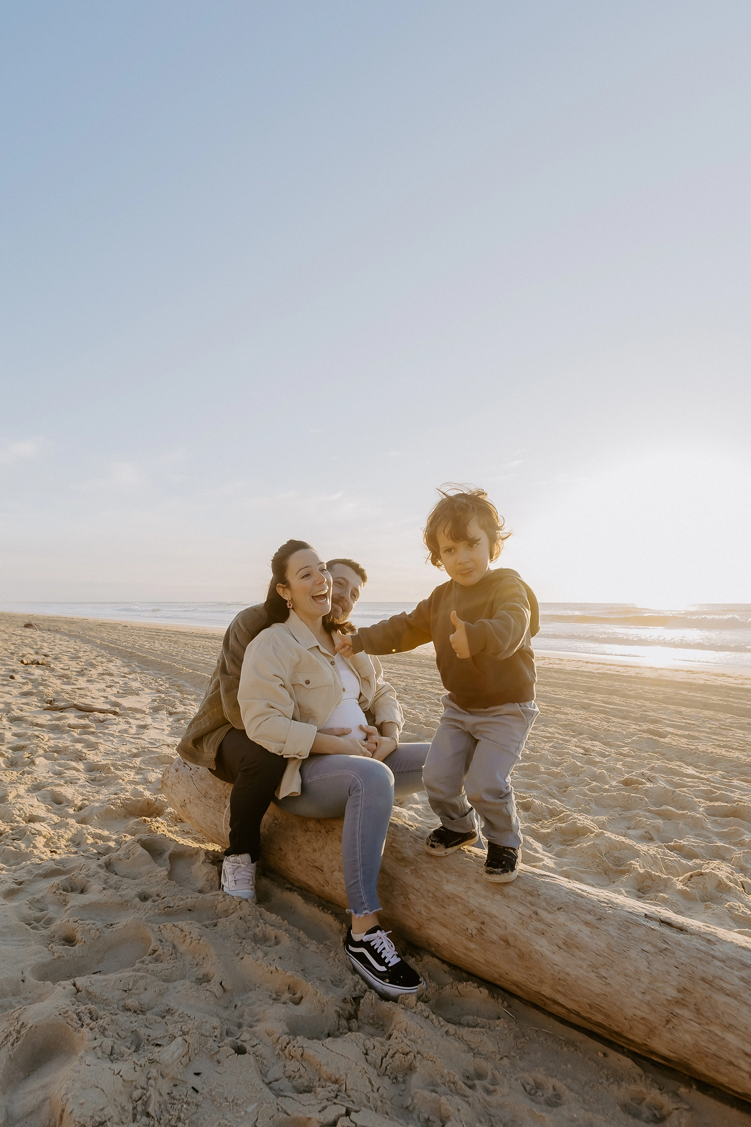 Couple souriant, main dans la main, attendant leur deuxième enfant sur le sable landais