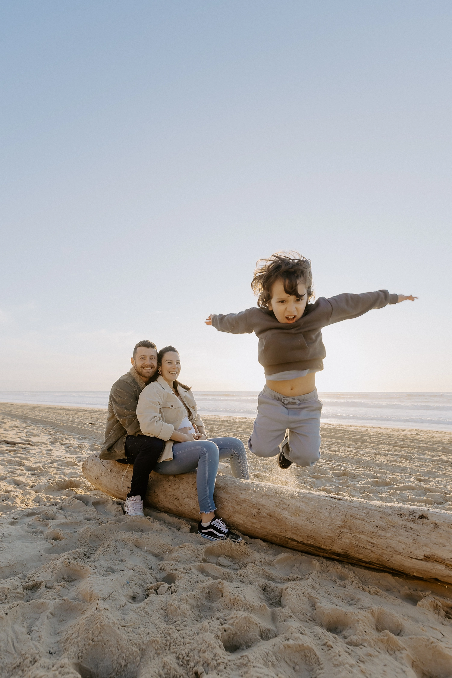 Couple souriant, main dans la main, attendant leur deuxième enfant sur le sable landais