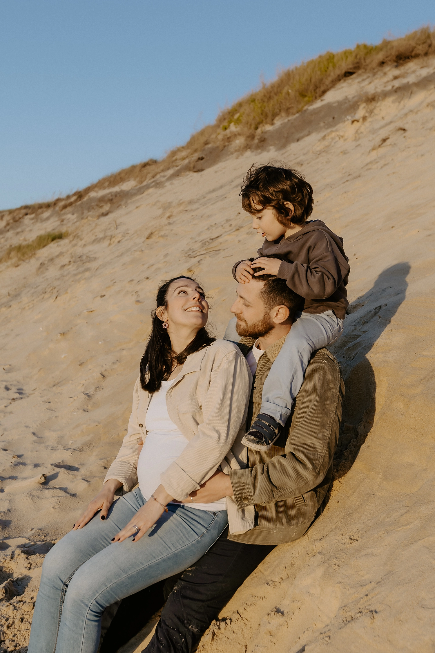 Couple souriant, main dans la main, attendant leur deuxième enfant sur le sable landais