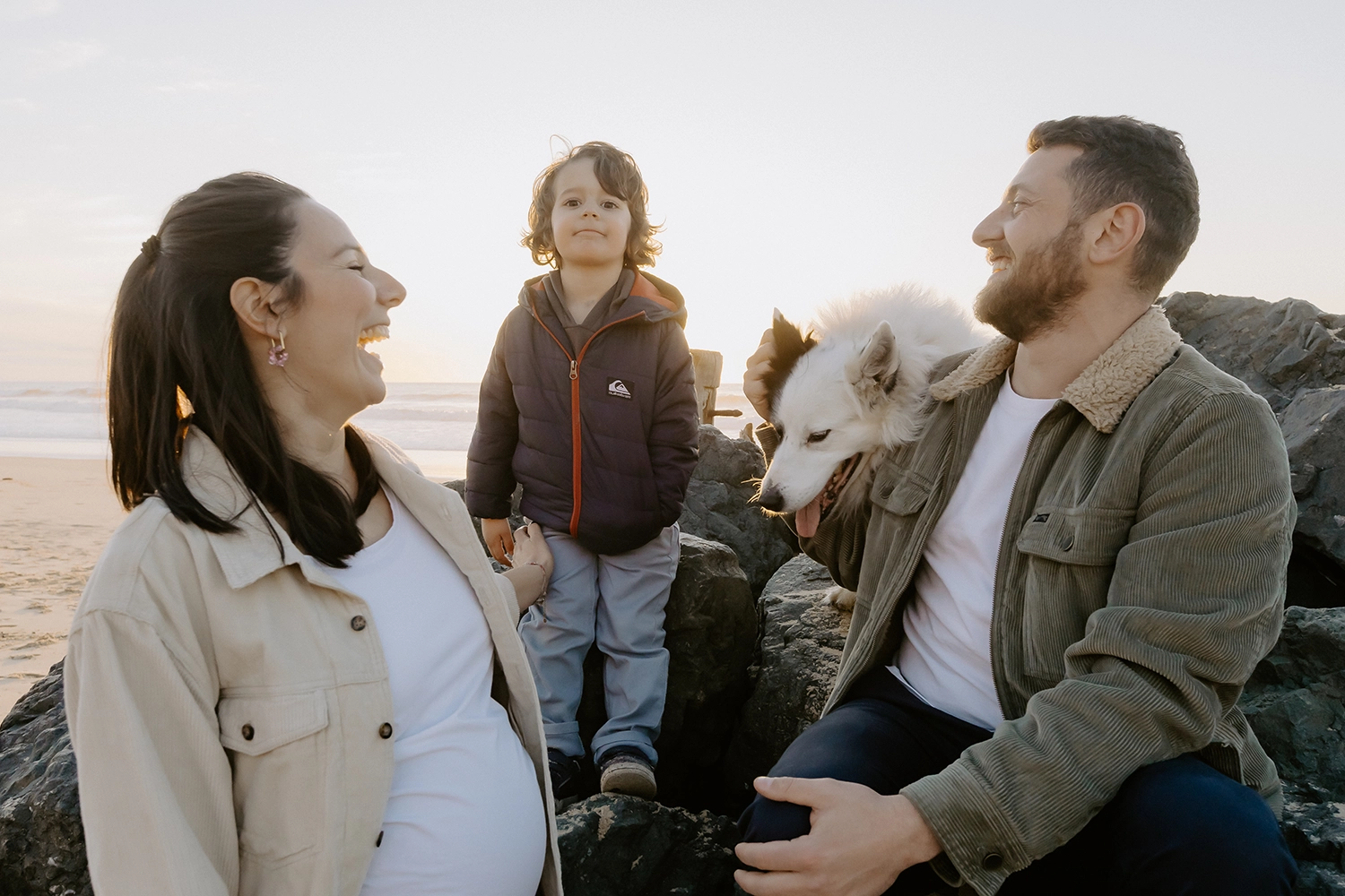 Couple souriant, main dans la main, attendant leur deuxième enfant sur le sable landais
