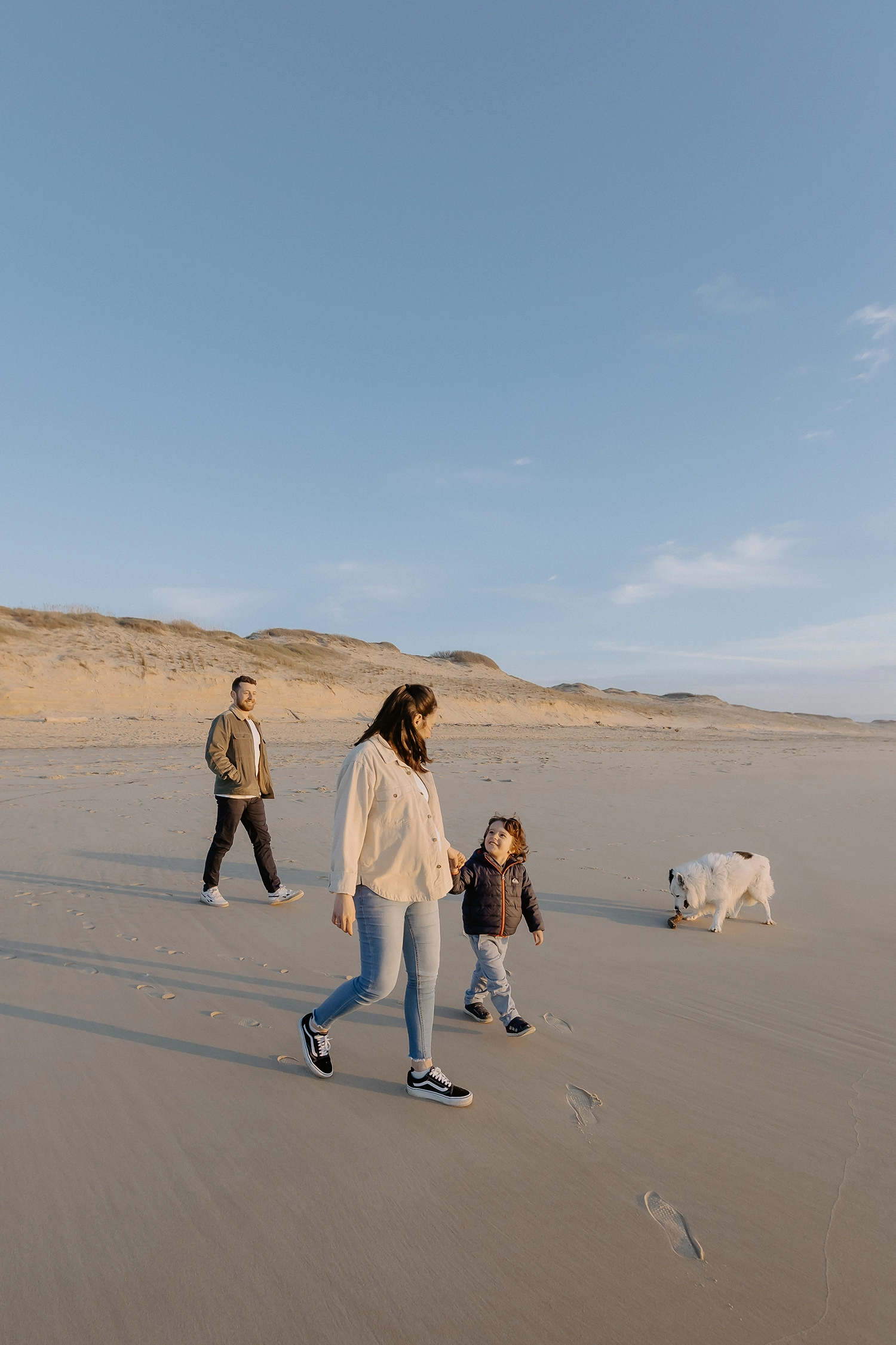 Couple souriant, main dans la main, attendant leur deuxième enfant sur le sable landais